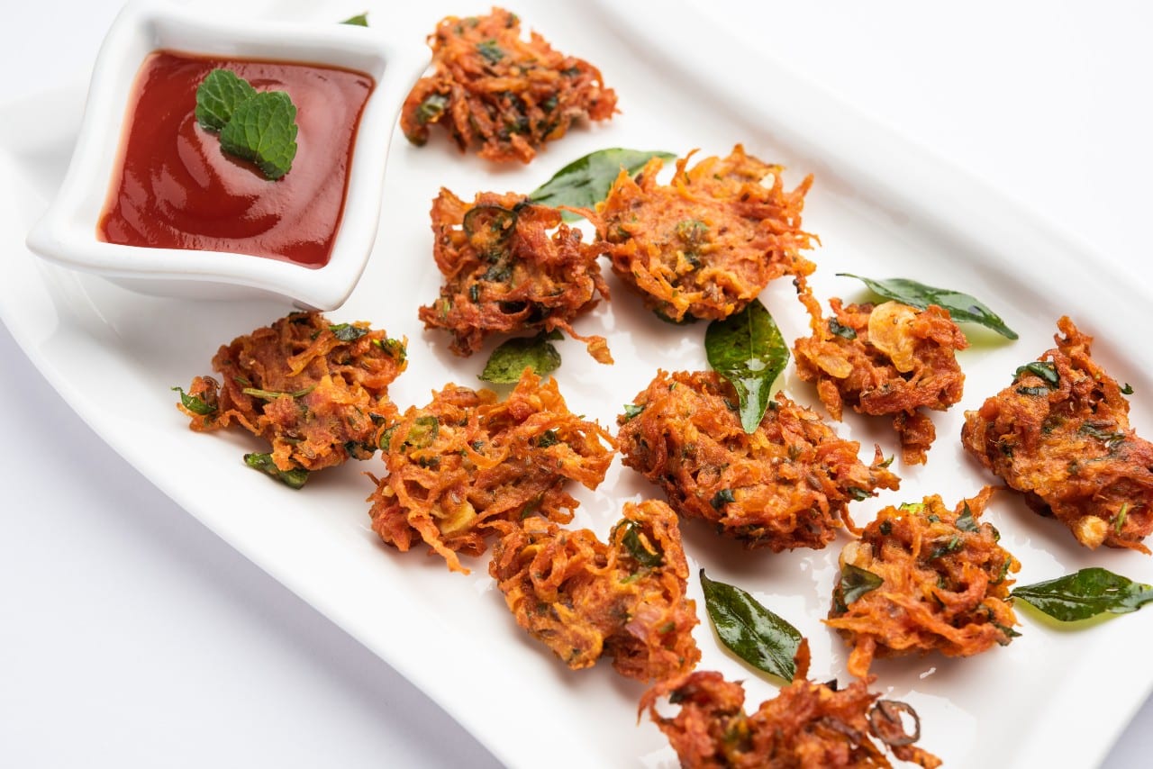 19 Must-Try Monsoon Recipes for Perfect Rainy Evenings 1 Crispy pakoras in a white plate
