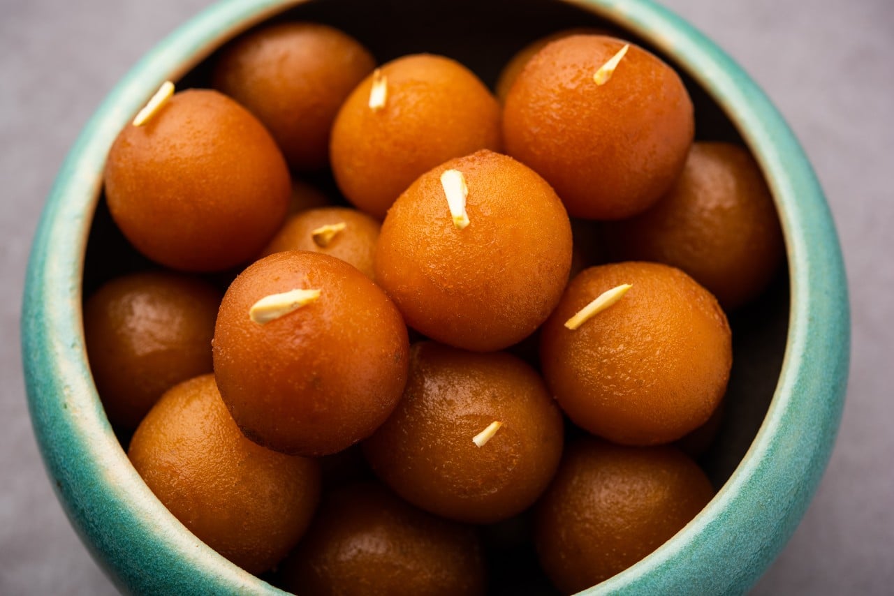 Delicious Indian sweet Gulab Jamun served in a blue bowl garnished with sliced almonds traditional dessert for festivals and celebrations