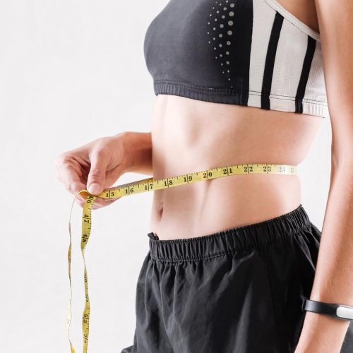 What are the Best Fat-Burning Foods to Include in Your Diet? 17 A fit woman with a measuring tape