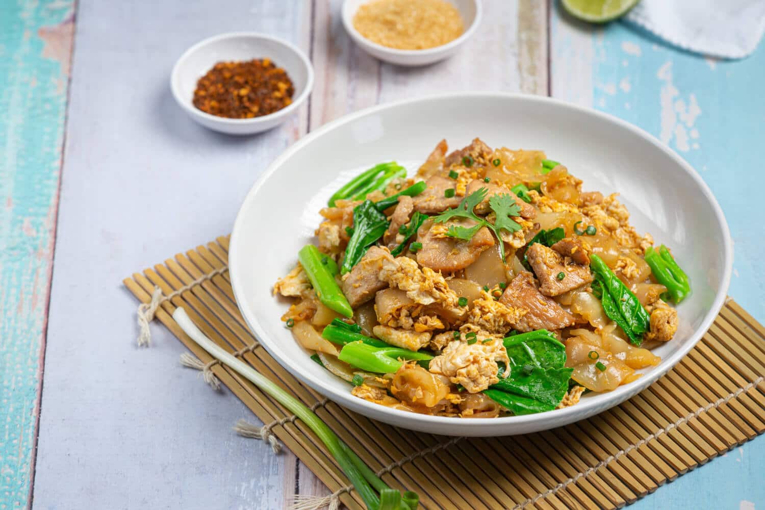 Which 25 Singapore Food Dishes Should You Try? 6 A white bowl of Pad See Ew consisting of stir fried wide rice noodles with pork egg and Chinese broccoli