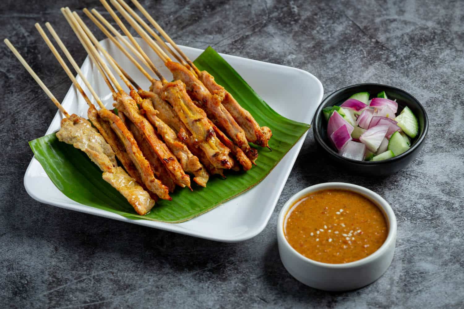Which 25 Singapore Food Dishes Should You Try? 5 Grilled pork satay skewers served on a banana leaf atop a white plate