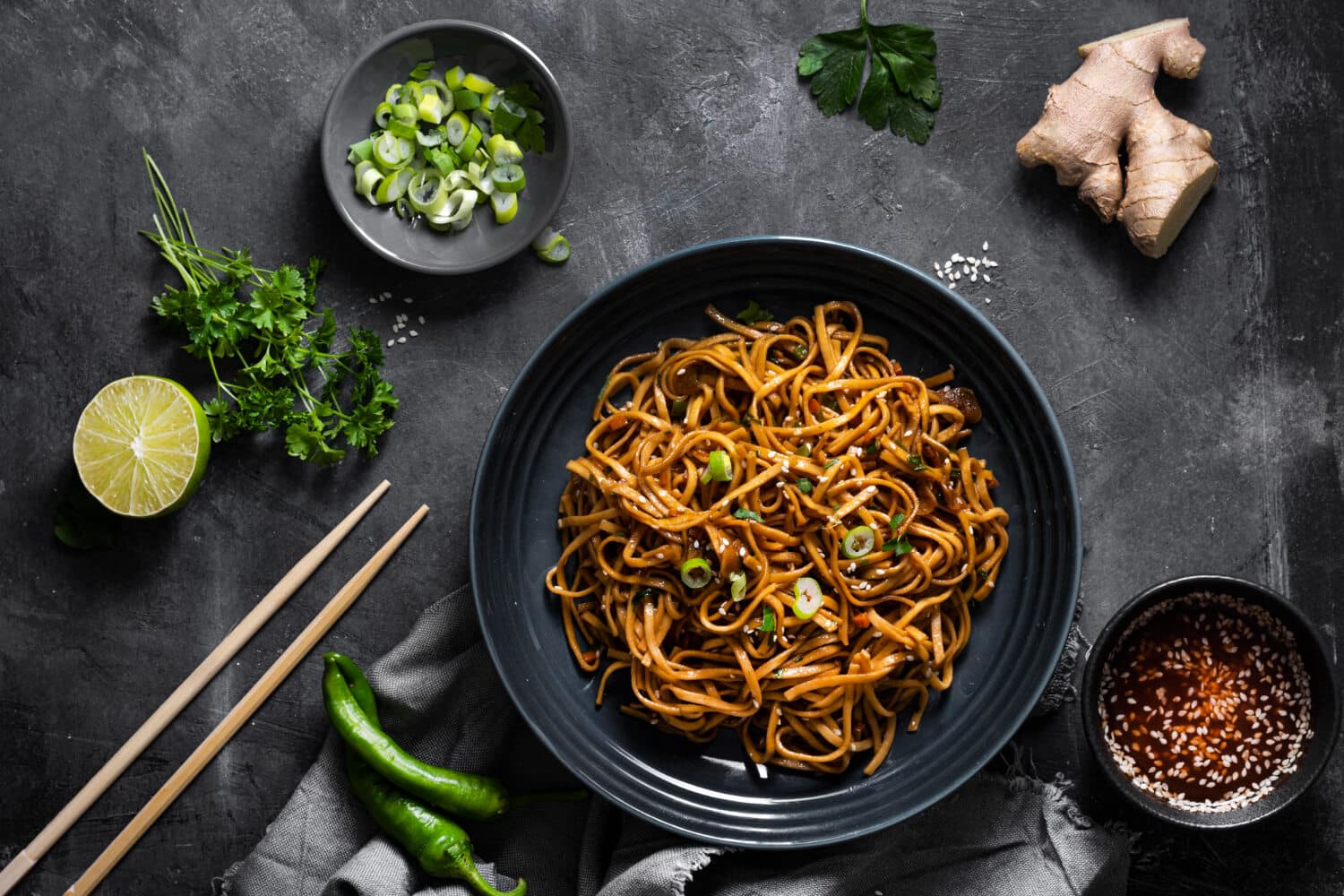 Which 25 Singapore Food Dishes Should You Try? 7 Top down view of a dark bowl of stir fried noodles garnished with sesame seeds and green onions