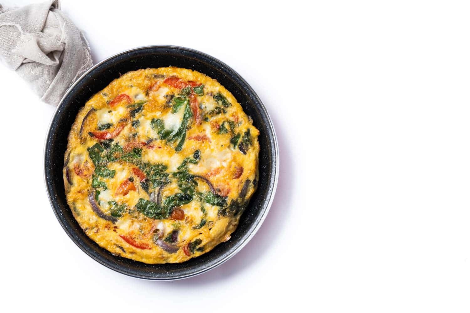 Which 25 Singapore Food Dishes Should You Try? 14 Top down view of a vegetable frittata with spinach red peppers and onions served in a black frying pan