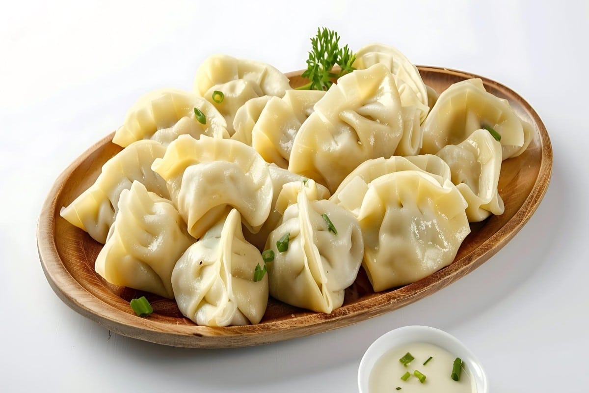 What Are 15 Chinese New Year Food Dishes You Must Try? 5 Steamed Chinese dumplings arranged on a wooden platter with dipping sauce a traditional Chinese New Year food symbolising wealth and togetherness