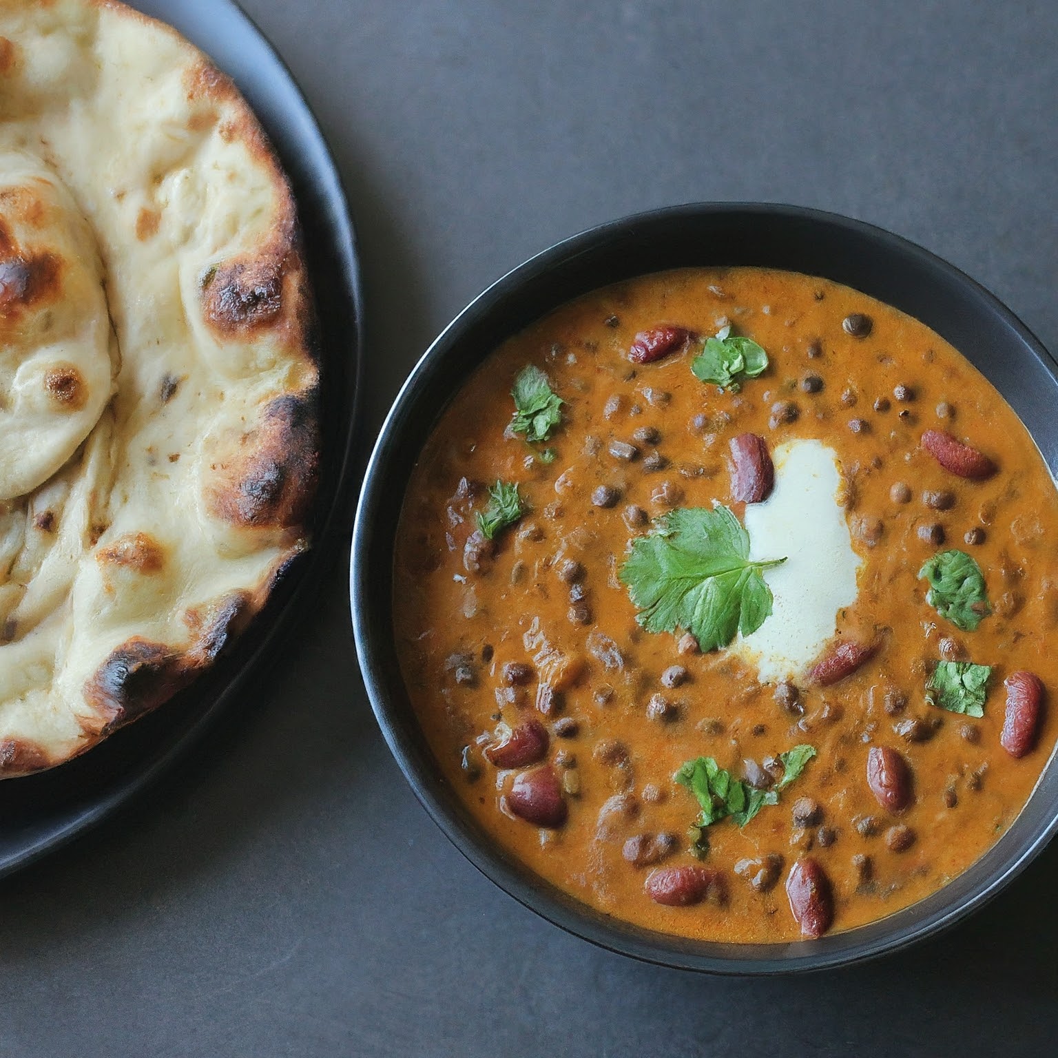 A steaming bowl of Dal Makhani, a creamy Indian lentil curry with black urad dal, red kidney beans, and fresh cilantro.