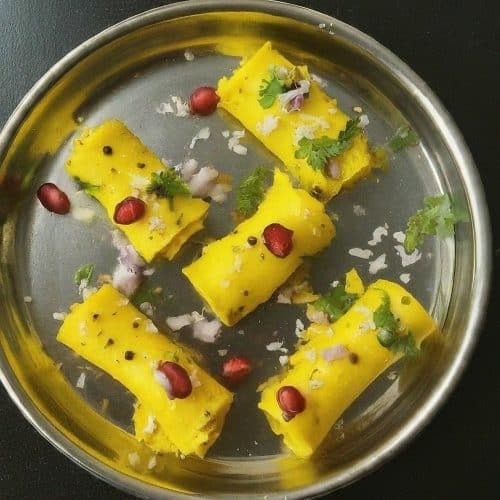 A close-up of rolled Khandvi, a savoury vegan Indian snack made from gram flour batter.