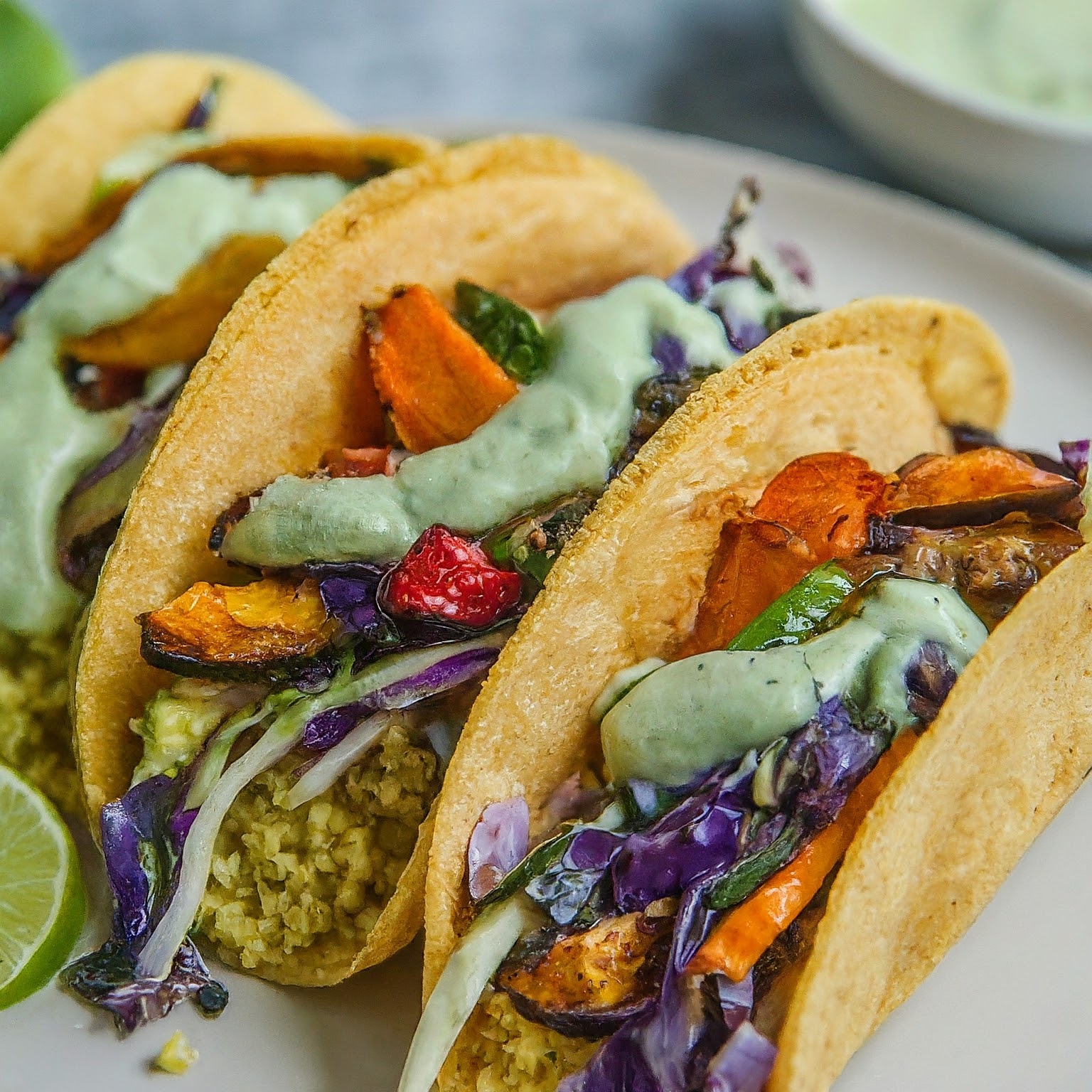 Two Millet Tacos with colourful roasted vegetables, zesty lime slaw, and avocado crema.