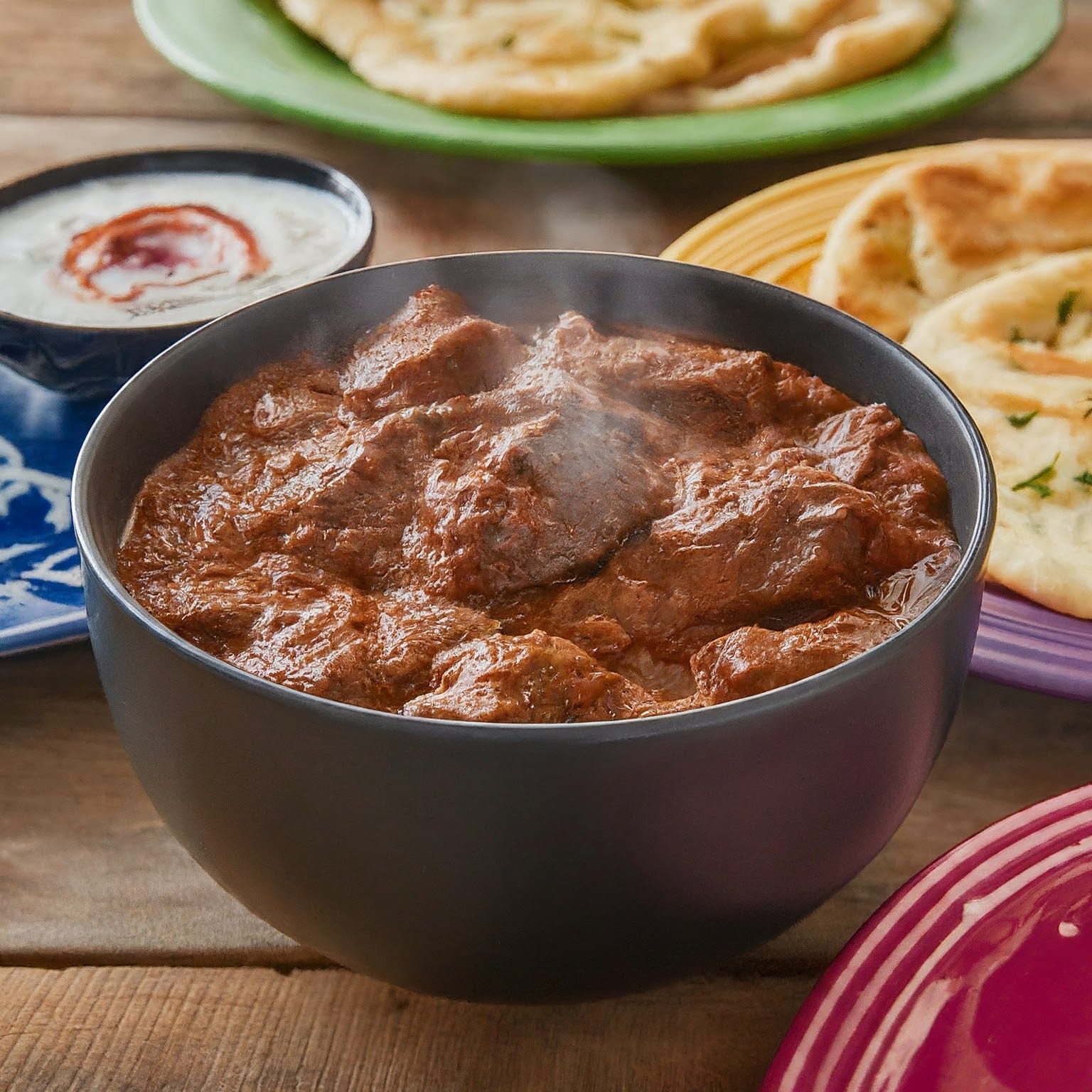 A deep red Rogan Josh curry with lamb can be served with rice.