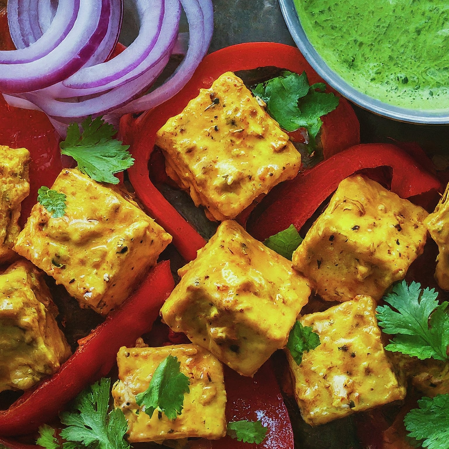Platter of colourful Yogurt and Spice-marinated Paneer Cubes with vegetables and mint chutney.