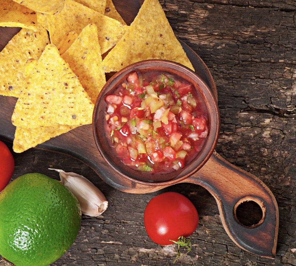 salsa with chips on a wooden plate
