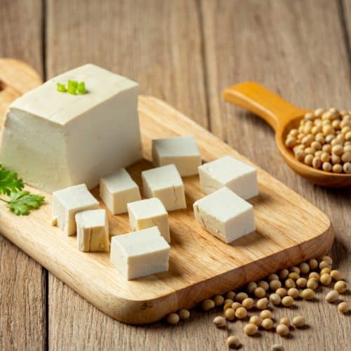 Cubes of paneer placed on a chopping board with coriander