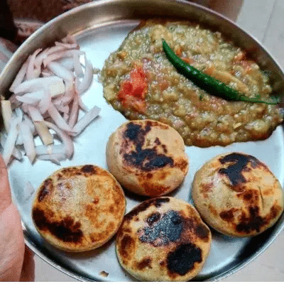 What Are the Most Famous Foods of Uttar Pradesh? 8 Batti chokha with roasted wheat balls mashed vegetable chokha green chili and sliced onions on a plate