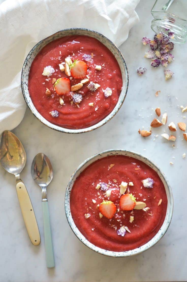Two bowls of Chilled Strawberry Rhubarb Soup topped with straberries and nuts