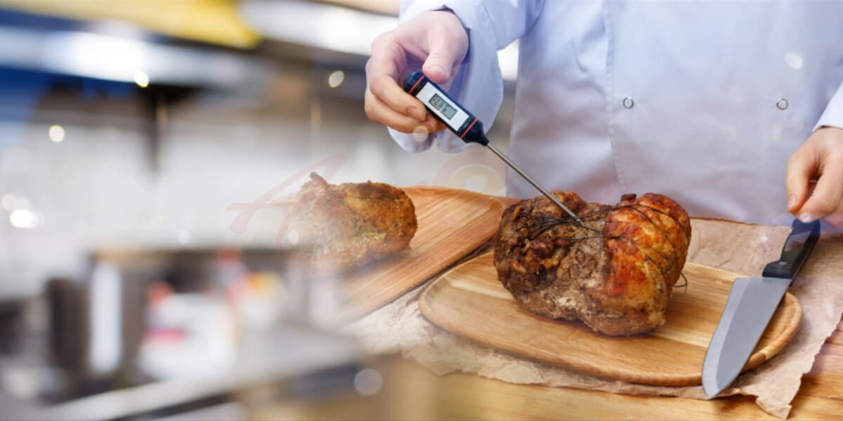 Cook measuring temperature of cooked meat on table