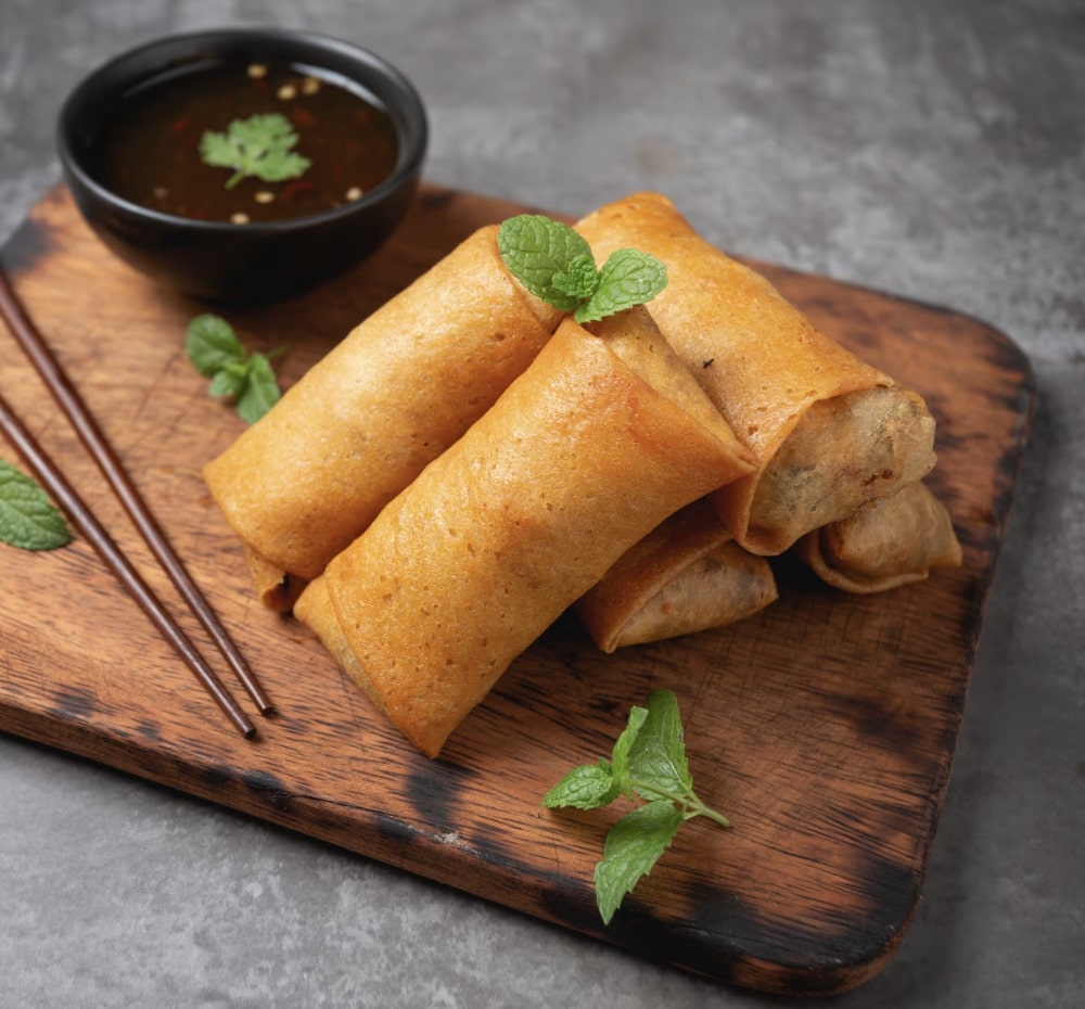 spring rolls and dip on a wooden plate 