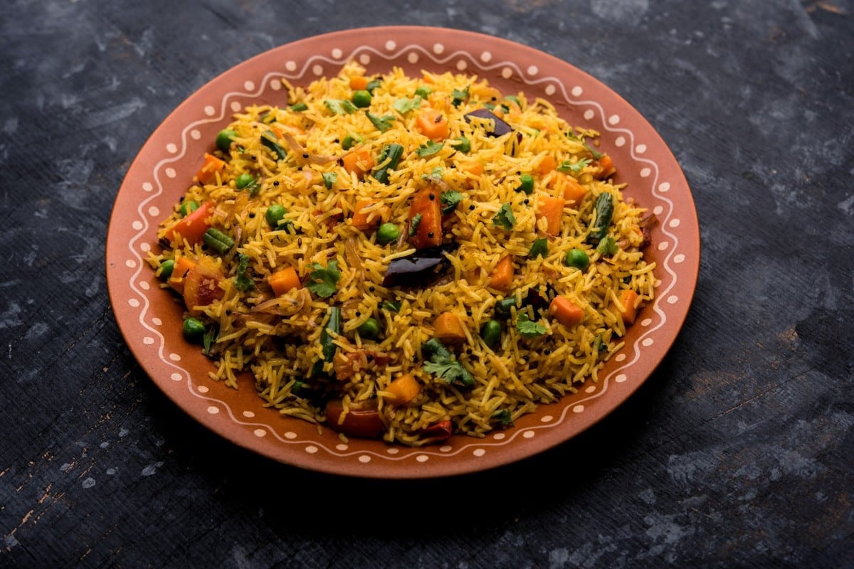 A plate of colourful vegetable pulao made with basmati rice peas carrots and spices garnished with fresh coriander