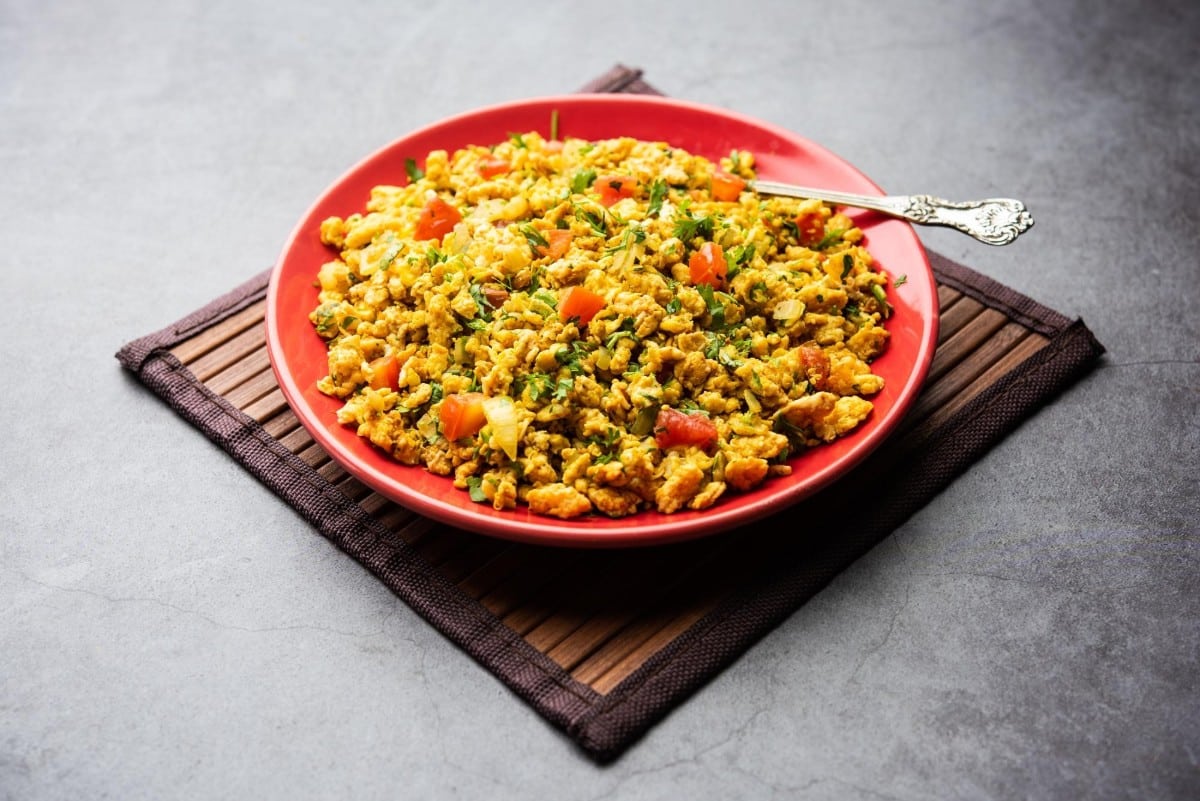 A plate of paneer bhurji cooked with tomatoes onions and spices garnished with fresh coriander