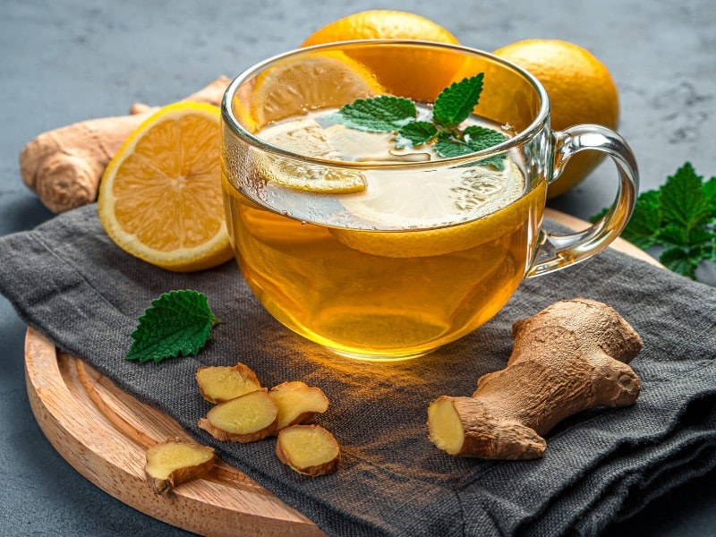 Which 10 Instant Hangover Cure Tips Should You Try Today? 6 Cup of ginger and lemon tea on a wooden tray surrounded by fresh ginger and lemons