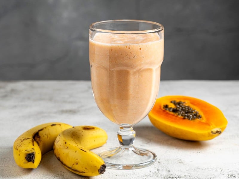 Which 10 Instant Hangover Cure Tips Should You Try Today? 5 Glass of papaya and banana smoothie beside fresh bananas and sliced papaya